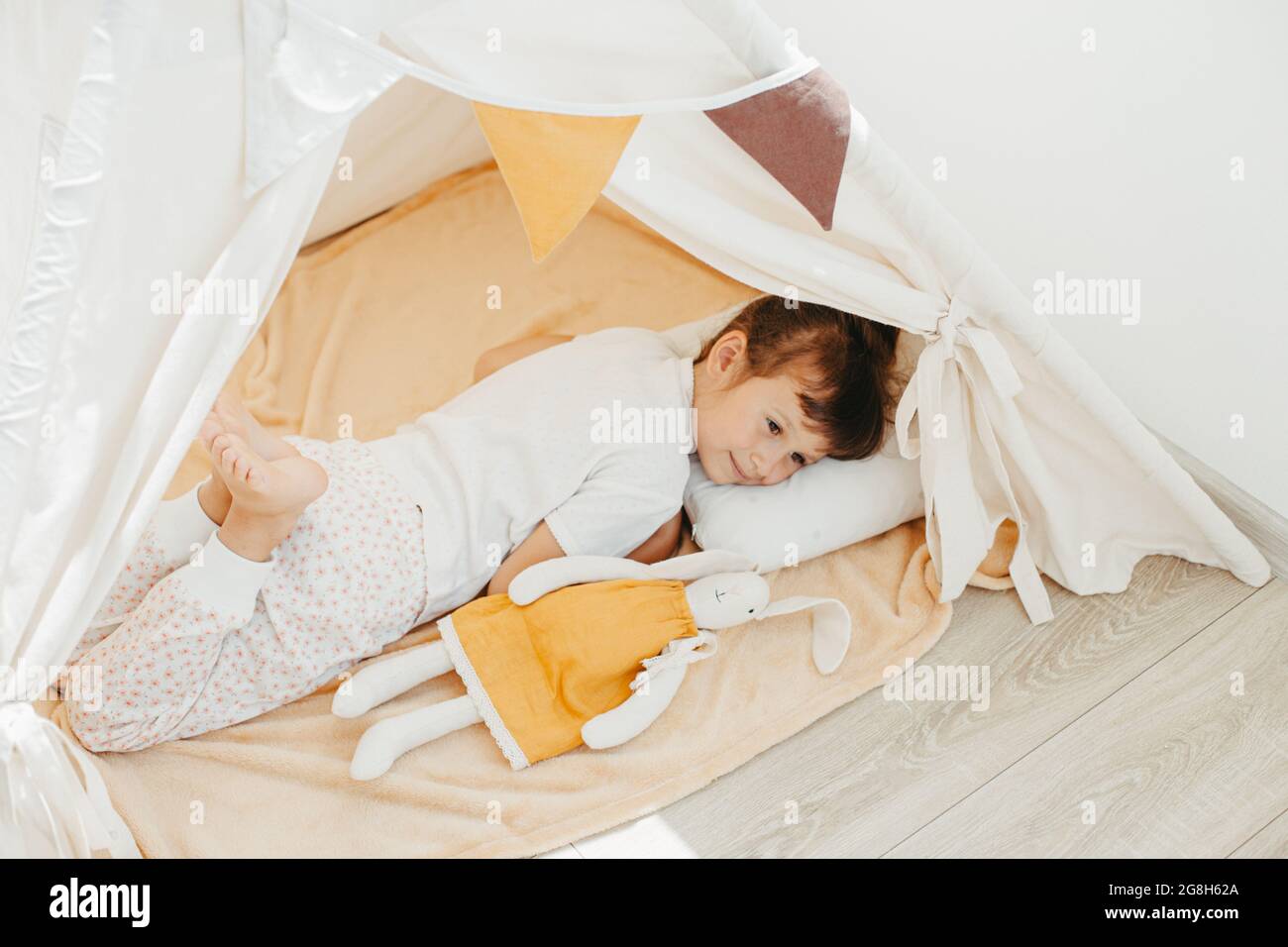 cute girl playing in teepee with fabric tilda bunny at home Stock Photo