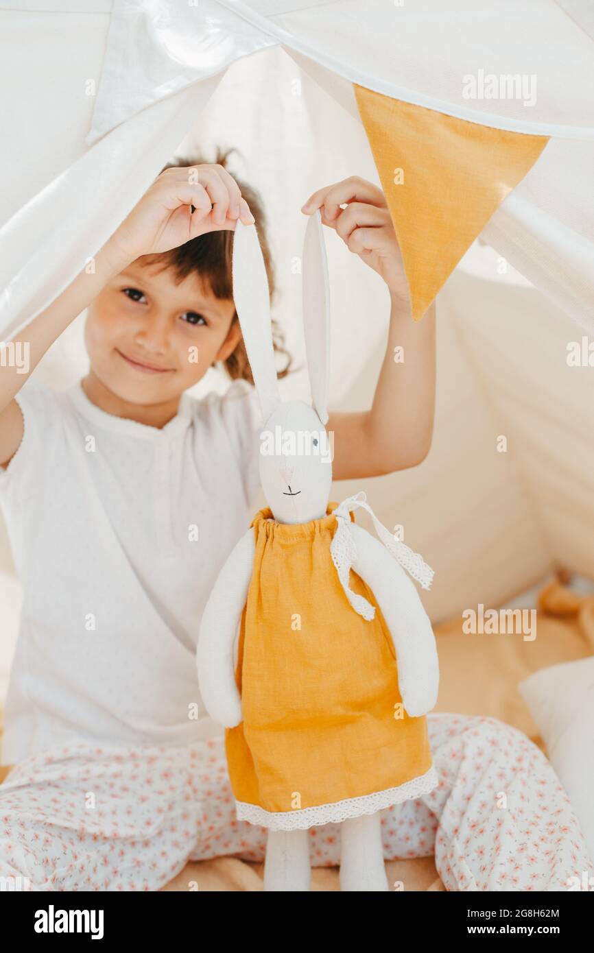 cute girl playing in teepee with fabric tilda bunny at home Stock Photo