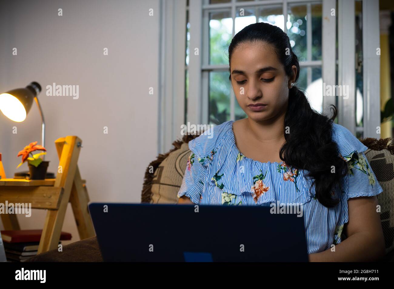 Pretty young Hispanic female typing on the computer from her living ...