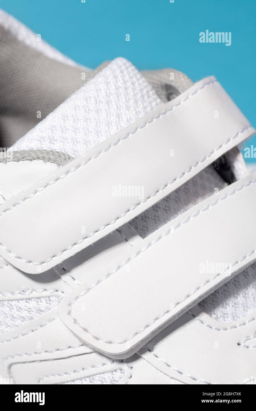 A close-up photo of the Velcro fastener of white sneakers. Children's sports sneakers made of leather with ventilation made of fabric, sewn with Stock Photo
