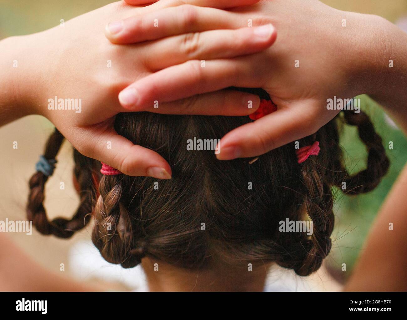 close-up of girl with braids and hands clasped behind her head Stock Photo