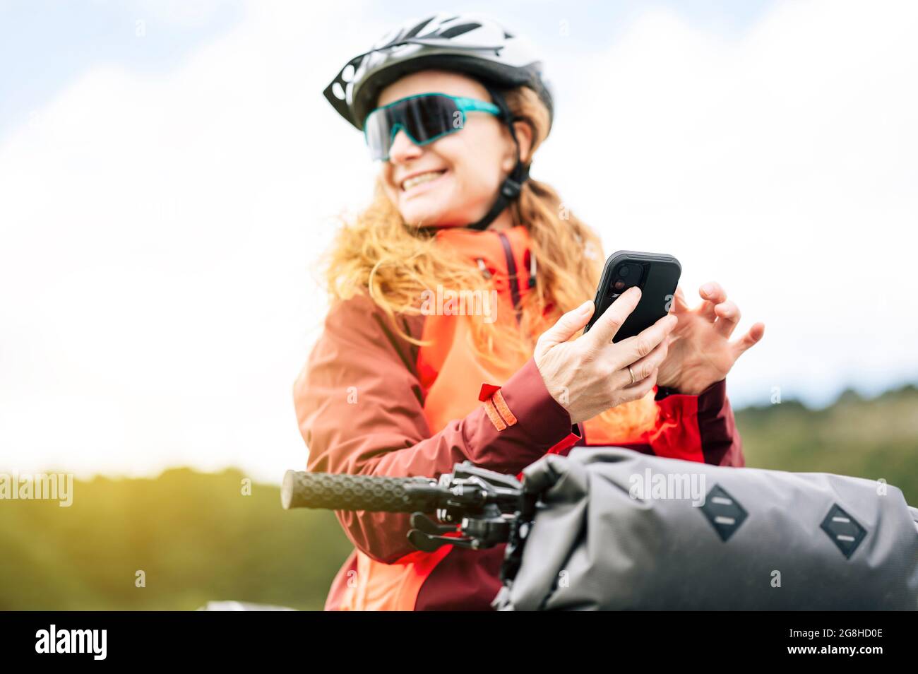 Woman enjoying with a mountain bike in nature, using smart phone Stock Photo