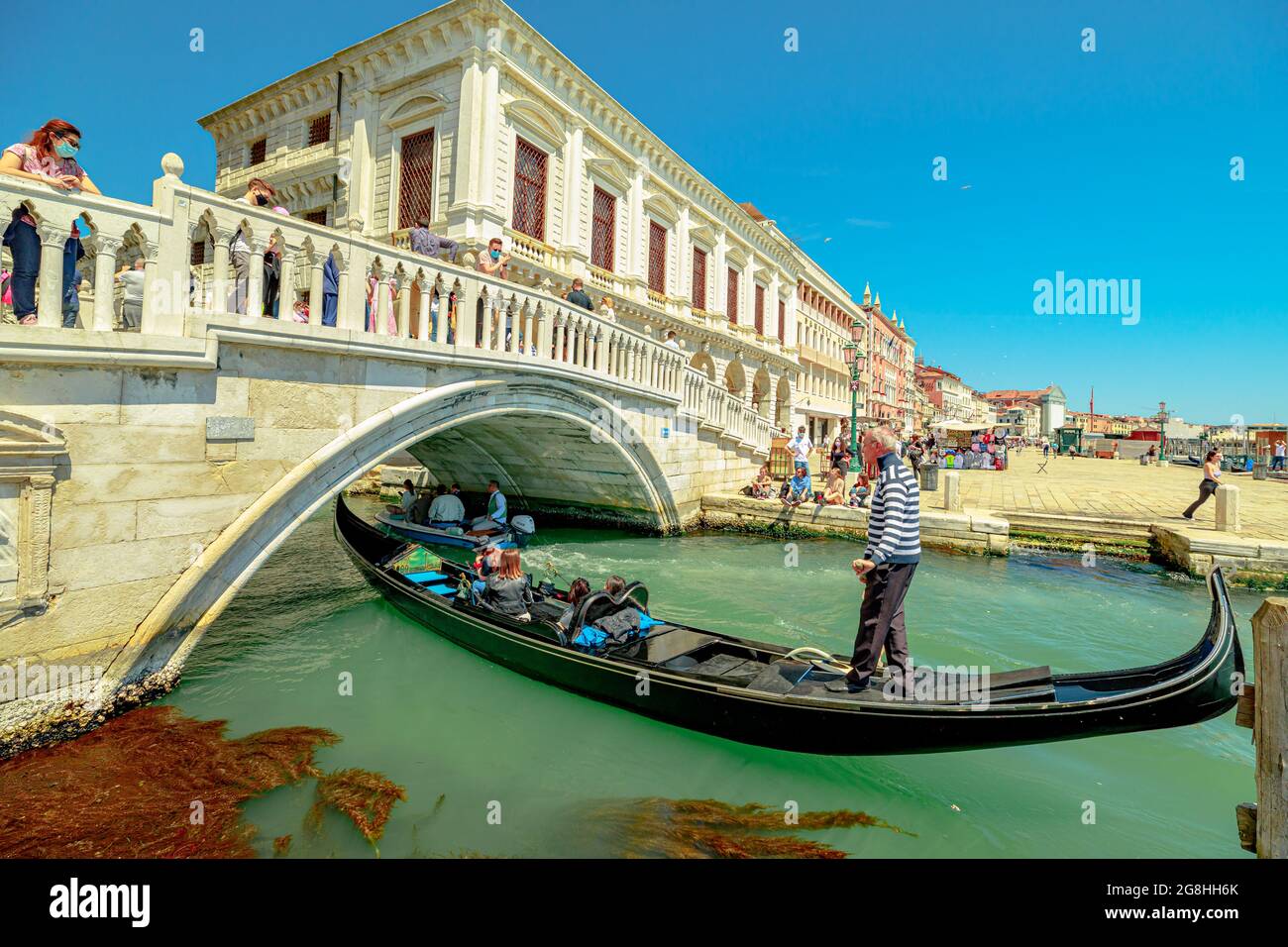Venice, Italy - May 9, 2021: Saint Mark square and traditional gondola boats with tourists in tour on Canal of Giudecca. People with face mask for Stock Photo