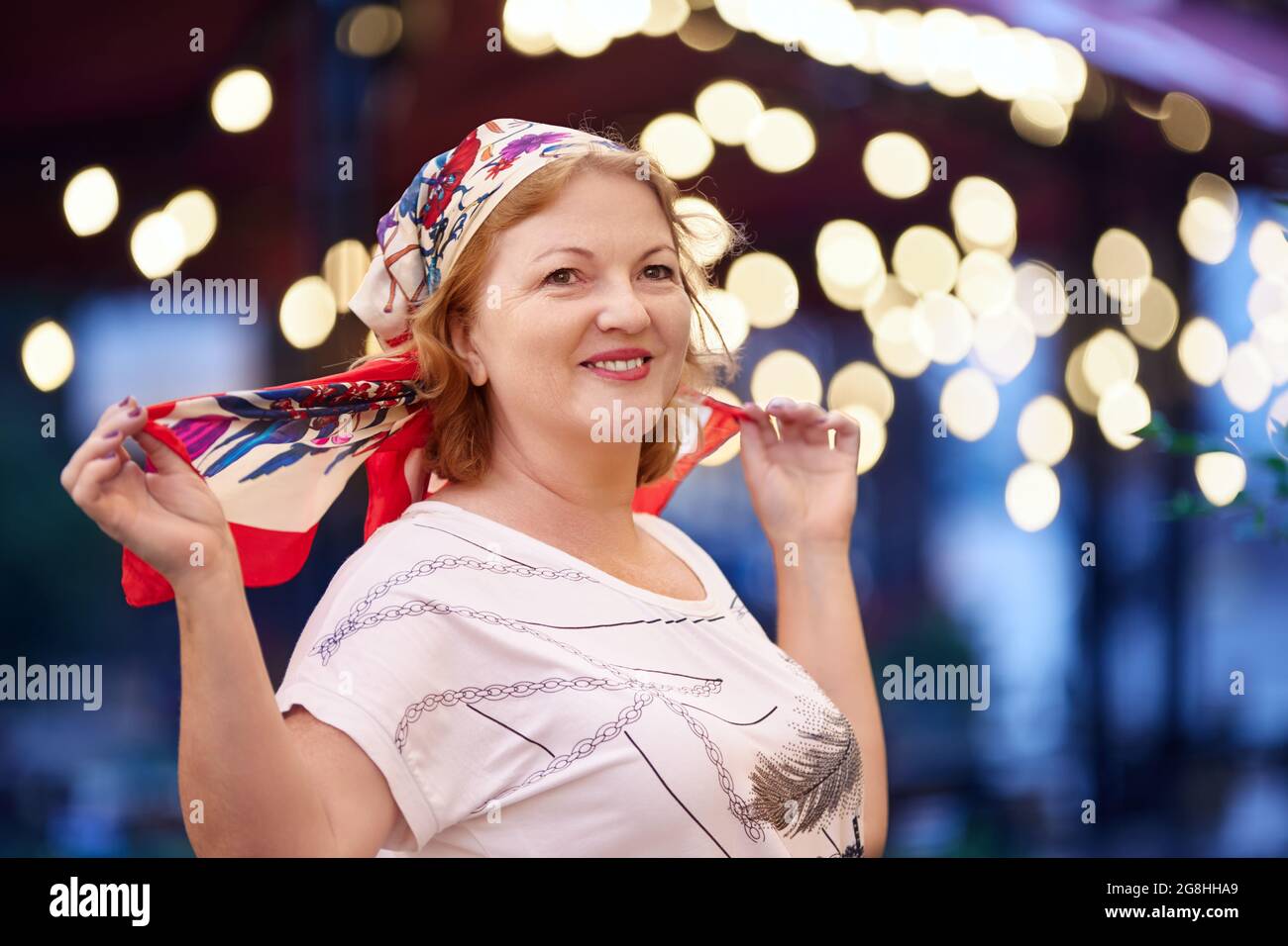 Smiling mature white woman wearing silk headscarf. Stock Photo