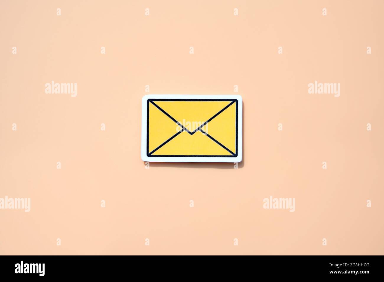 Yellow message sign or envelope icon against a salmon-colored background Stock Photo