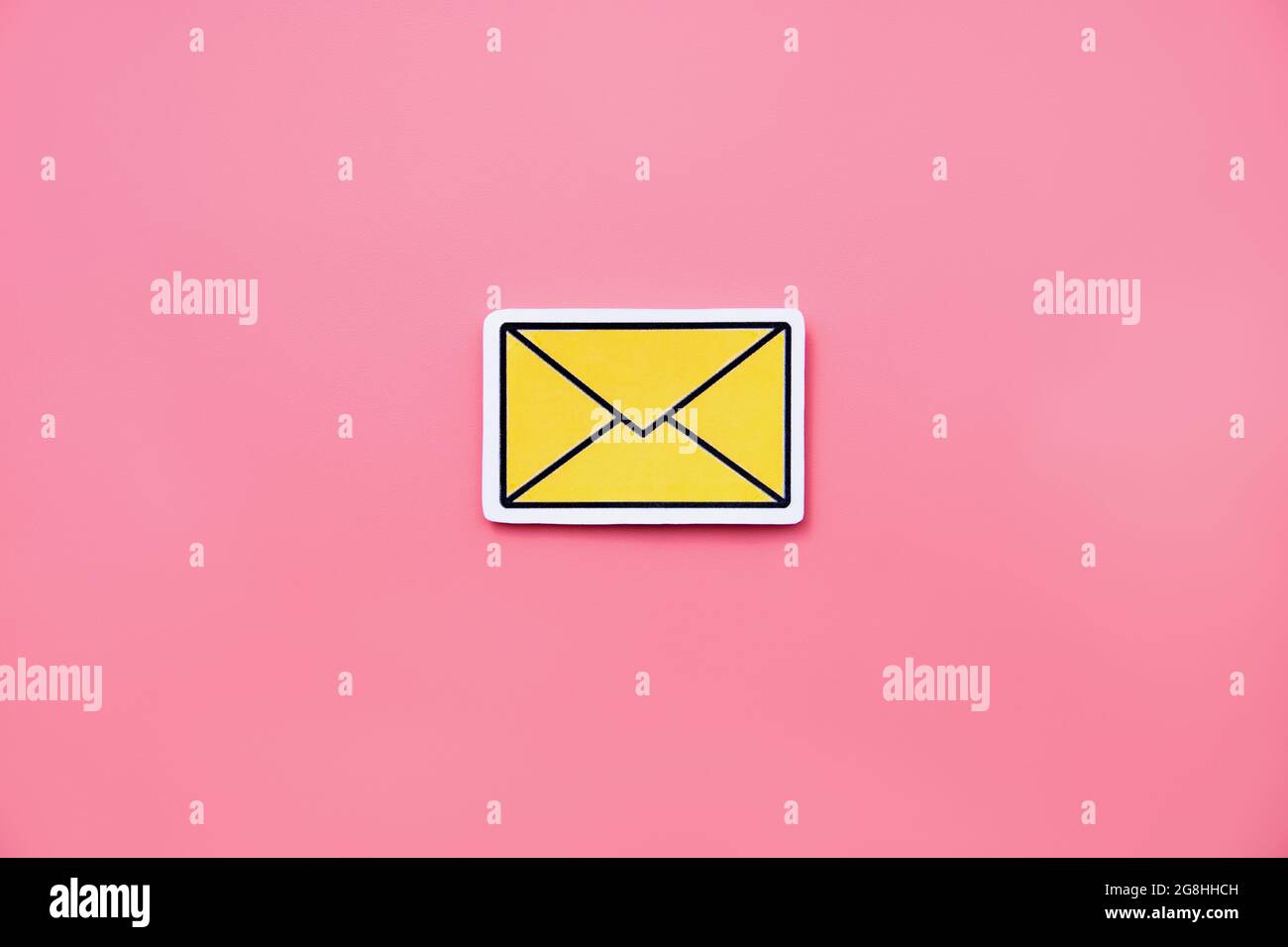Yellow message sign or envelope icon against a pink background Stock Photo