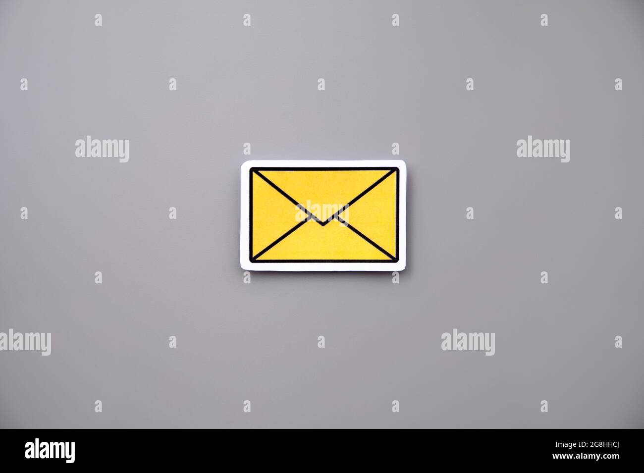 Yellow message sign or envelope icon against a grey background Stock Photo