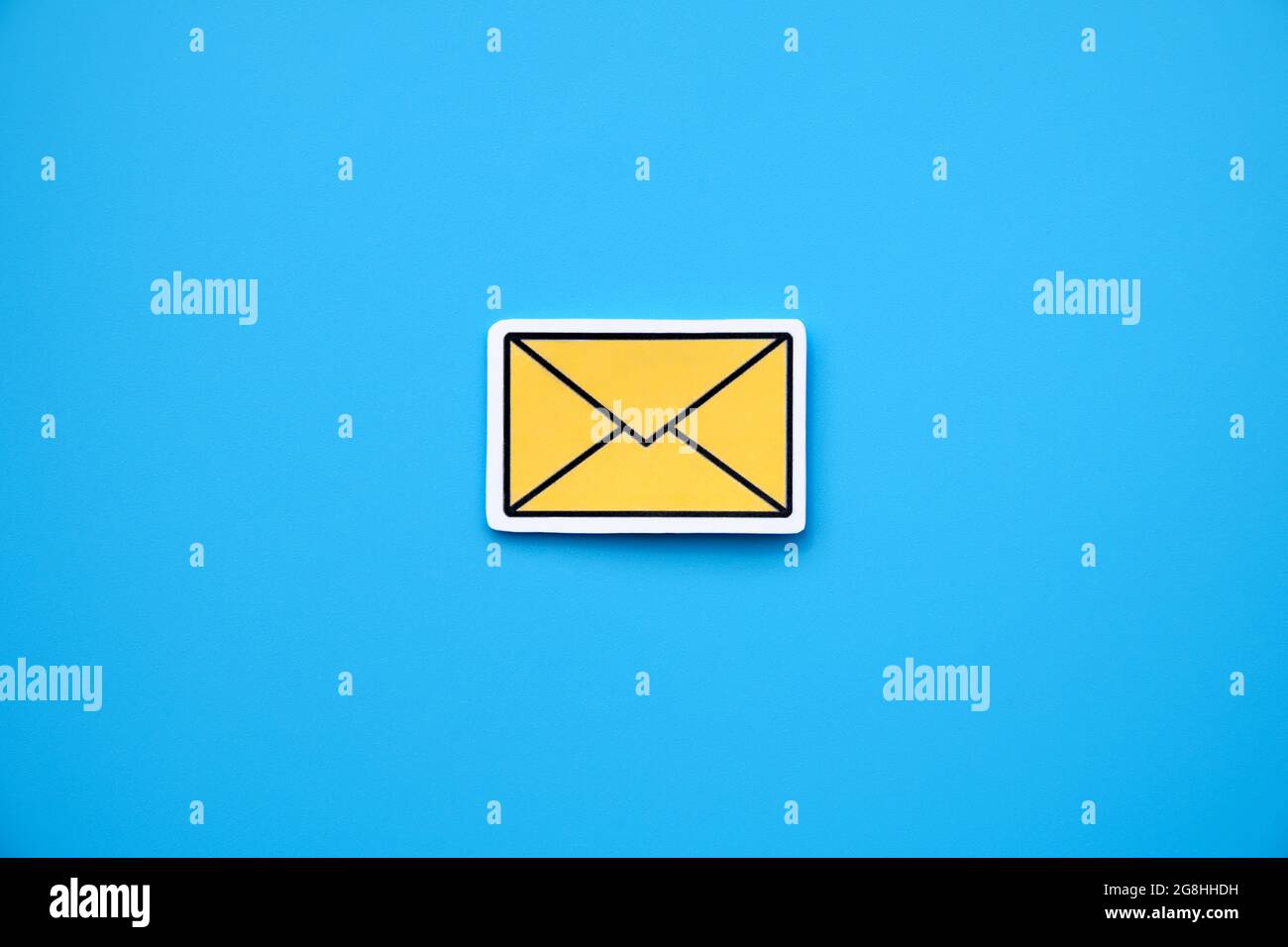 Yellow message sign or envelope icon against a blue background Stock Photo