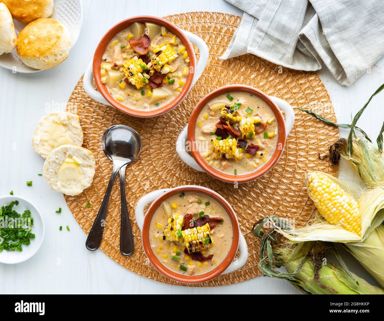 Top down view of three bowls of chicken and corn chowder soup served with biscuits.  Stock Photo