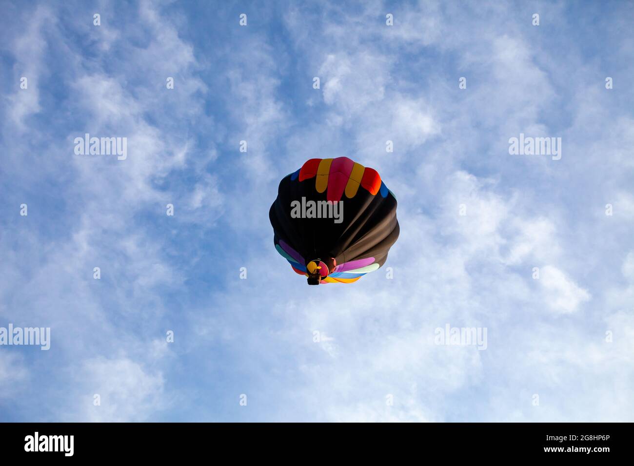 Colorful hot air balloon floating in a white and blue sky in central ...