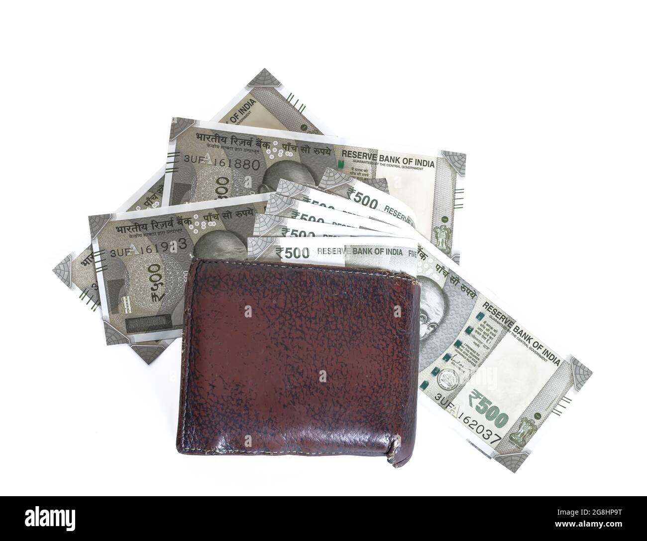 Brown leather wallet with scattered Indian 500 rupee bills around it on an isolated white background Stock Photo