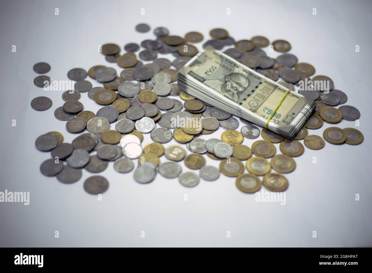Pile of scattered Indian coins and rupee bills on a white background ...