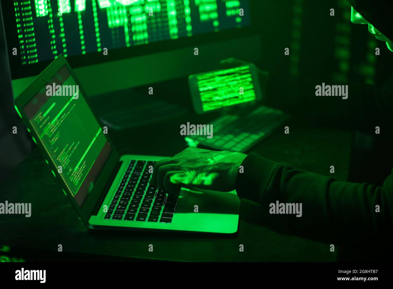 Hacker with mobile phone using computers in dark room Stock Photo