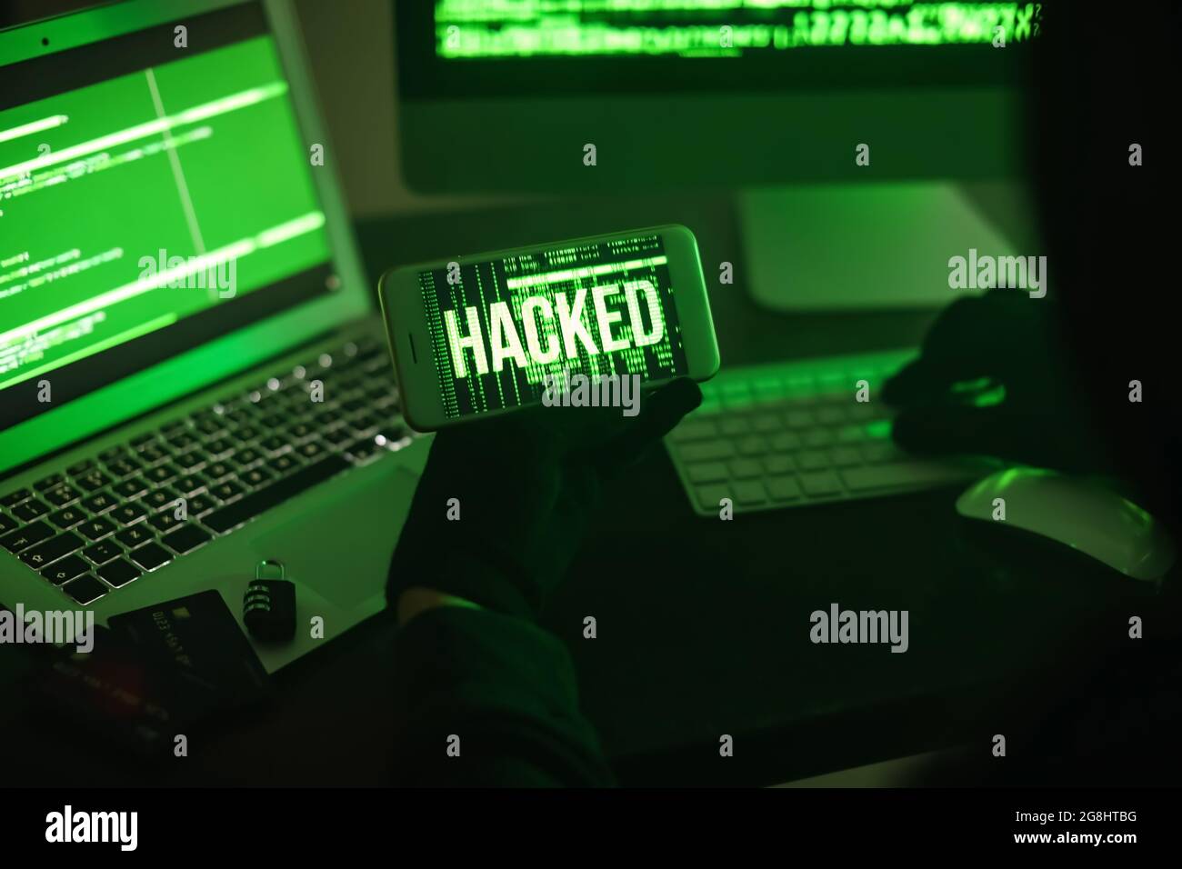 Hacker with mobile phone using computers in dark room Stock Photo - Alamy