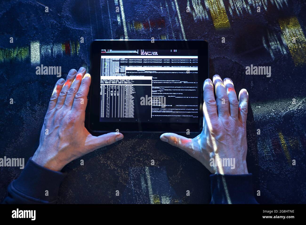 Hands of hacker with tablet computer on dark background Stock Photo