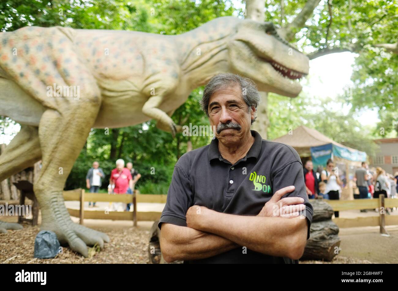 Leipzig, Germany. 20th July, 2021. Don Lessem, paleontologist and author, stands in front of a model of Tyrannosaurus rex at Leipzig Zoo. The life-size likeness is part of the exhibition 'The Gigantic Dino Adventure' on display there. Don Lessem also worked as a consultant for the film Jurassic Park. Credit: Sebastian Willnow/dpa-Zentralbild/dpa/Alamy Live News Stock Photo