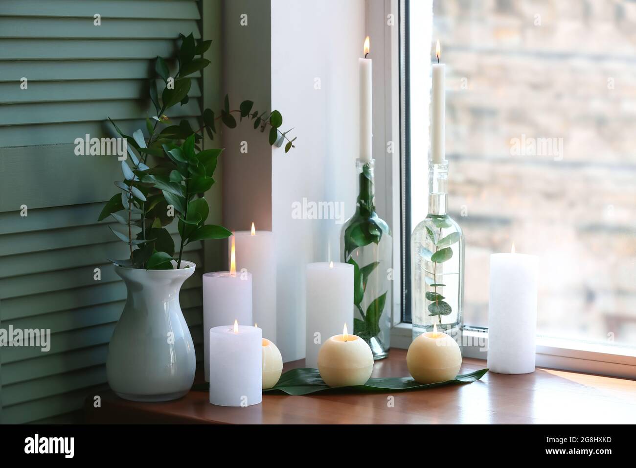 Burning candles with vase on windowsill Stock Photo Alamy