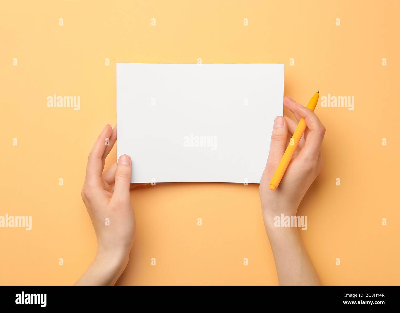 Woman holding blank sheet of paper and pen on color background Stock ...