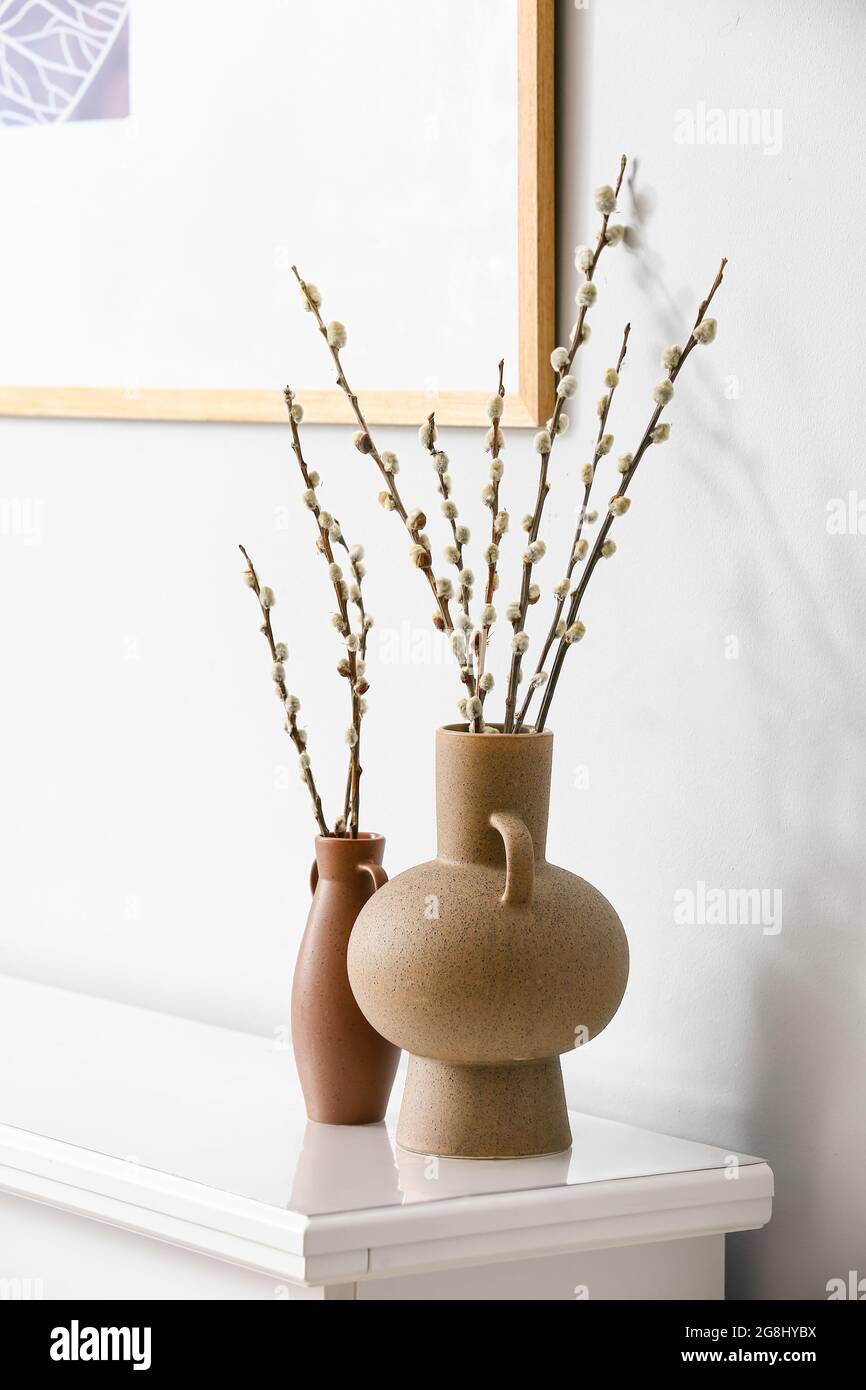 Vases with willow branches on shelf near light wall Stock Photo Alamy