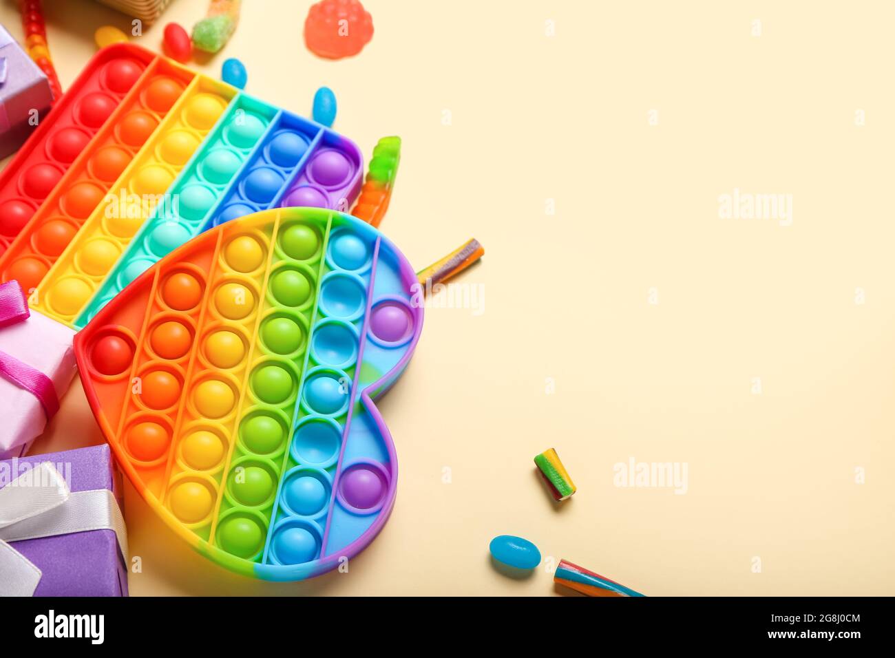 Pop it fidget toys and gifts on color background Stock Photo - Alamy