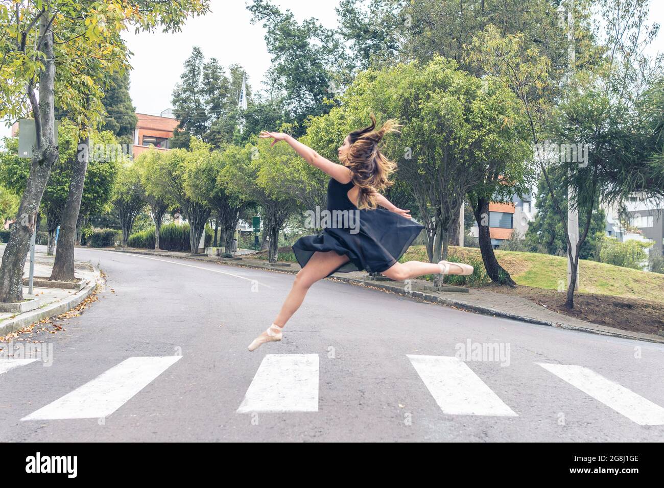 Ballet dancer running and dancing across a crosswalk on a street Stock Photo