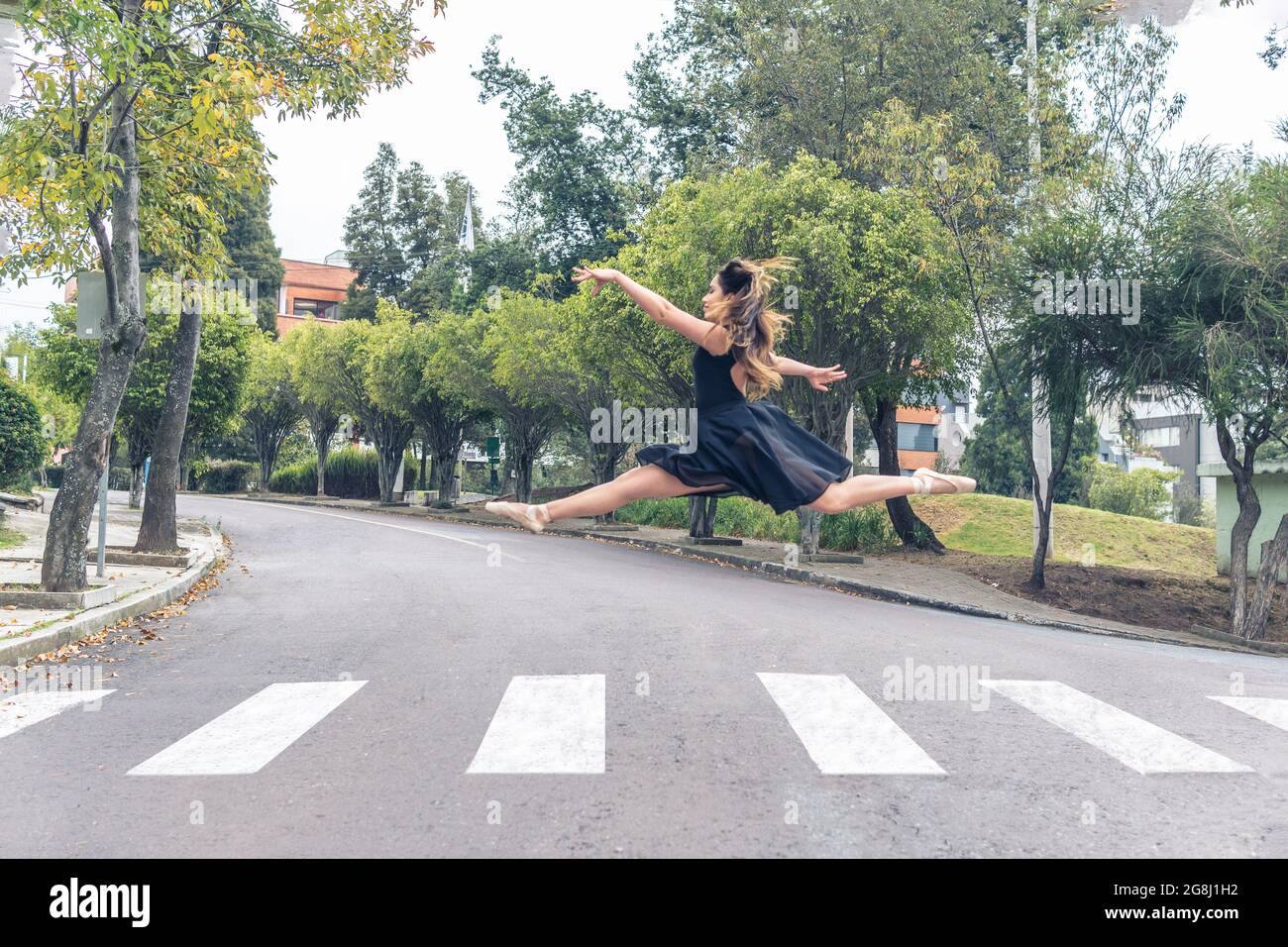 Ballet dancer performing a grand jete on a pedestrian crossing in the street Stock Photo