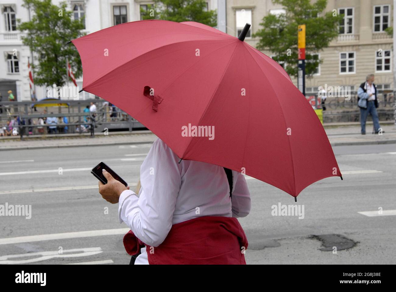 COPENHAGEN /DENMARK- Female under red umbrella waiting for bus at bus stop  30 July 2014 (Photo by Francis Dean/Deanpictures Stock Photo - Alamy