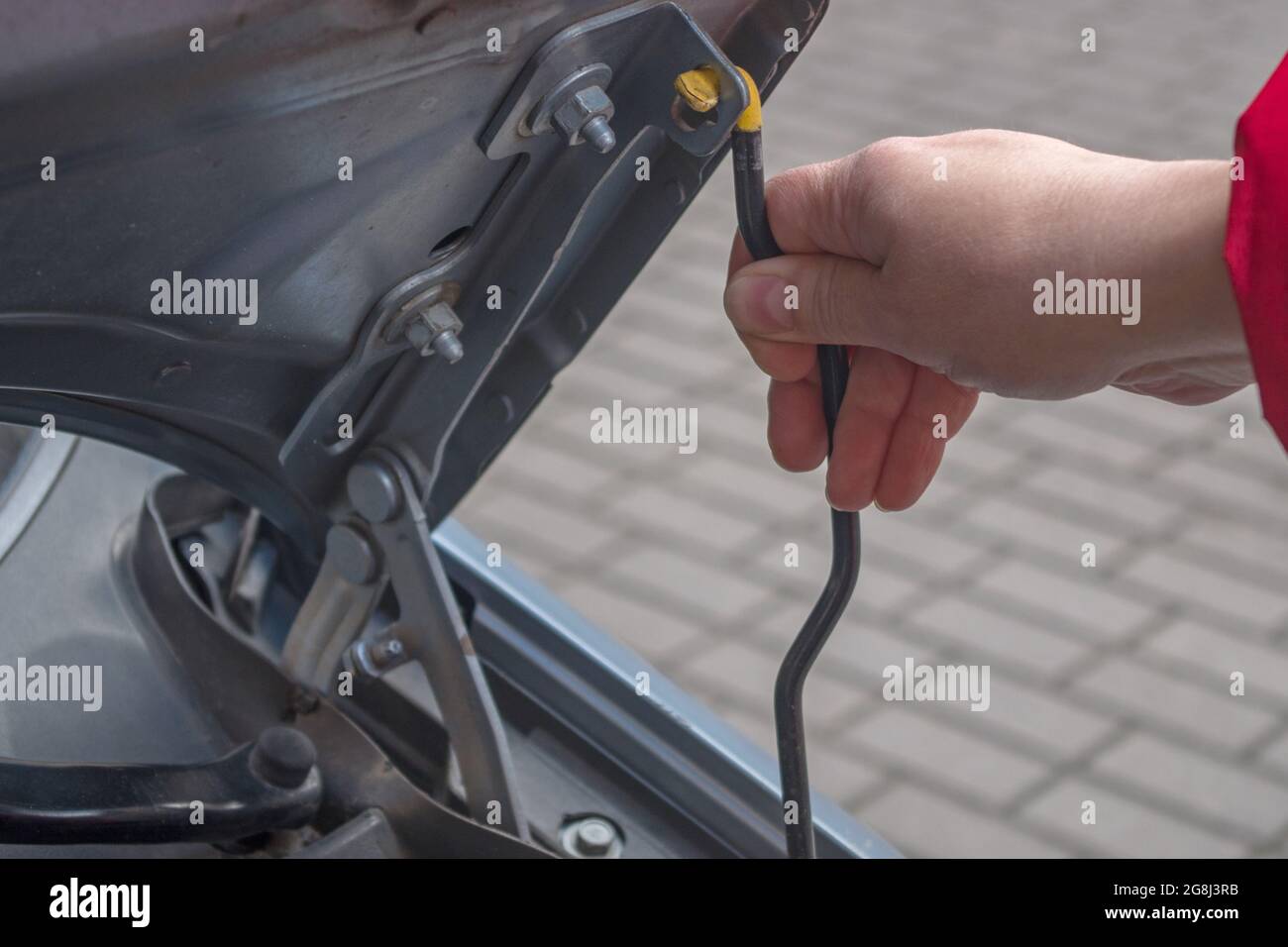 The female right hand holds the stop for the hood cover, placing it in the retainer for car maintenance. Concept: a woman performs a man's job of chec Stock Photo