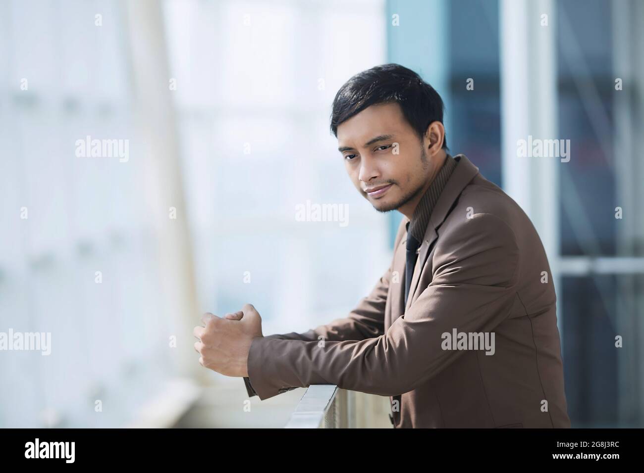 Businessman in brown suit. Thinking. Company background. Glass building.Take a close-up of the head and face Stock Photo