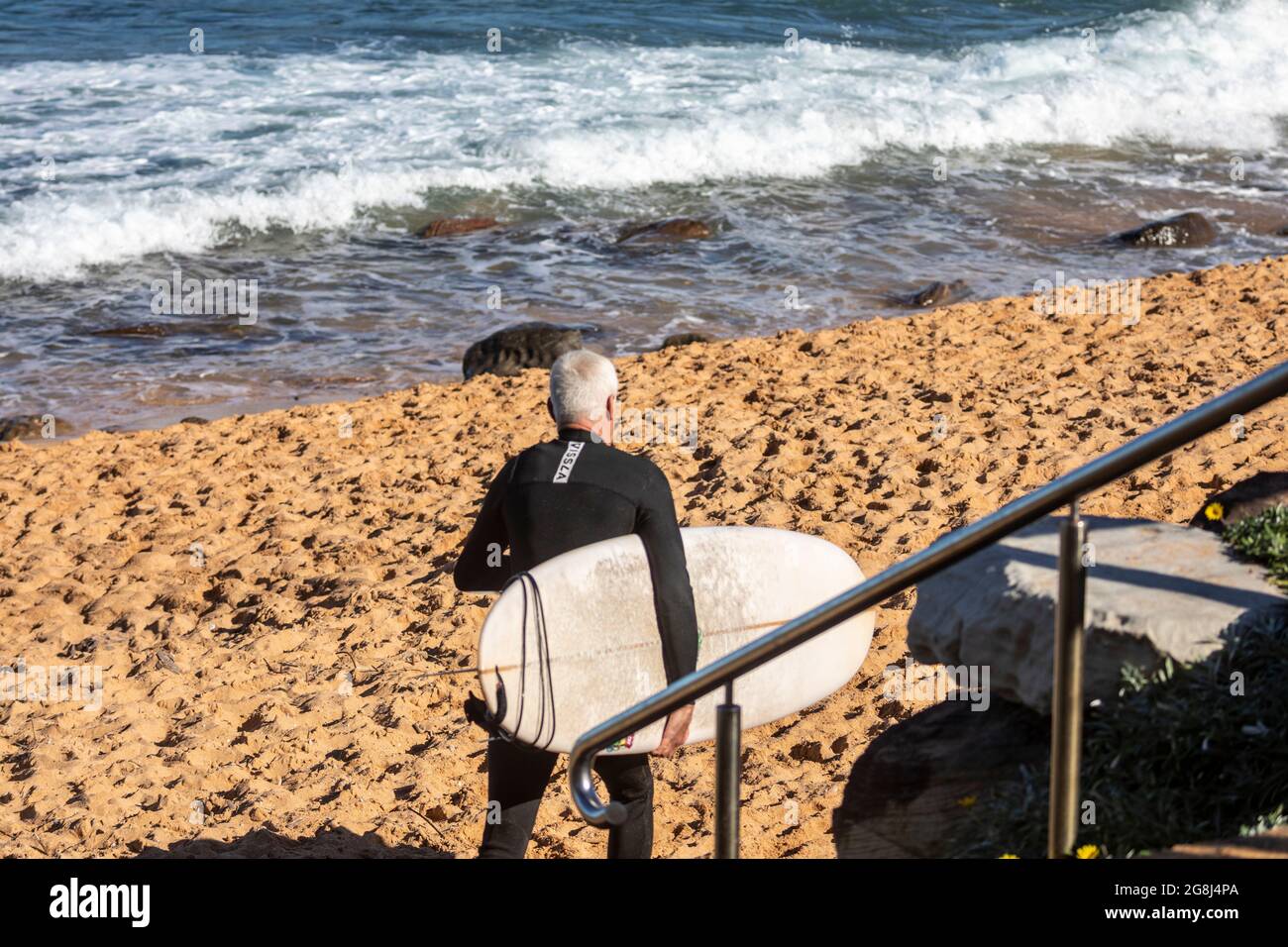 Middle aged Australian surfer carrying his surfboard to the ocean,Sydney,Australia Stock Photo