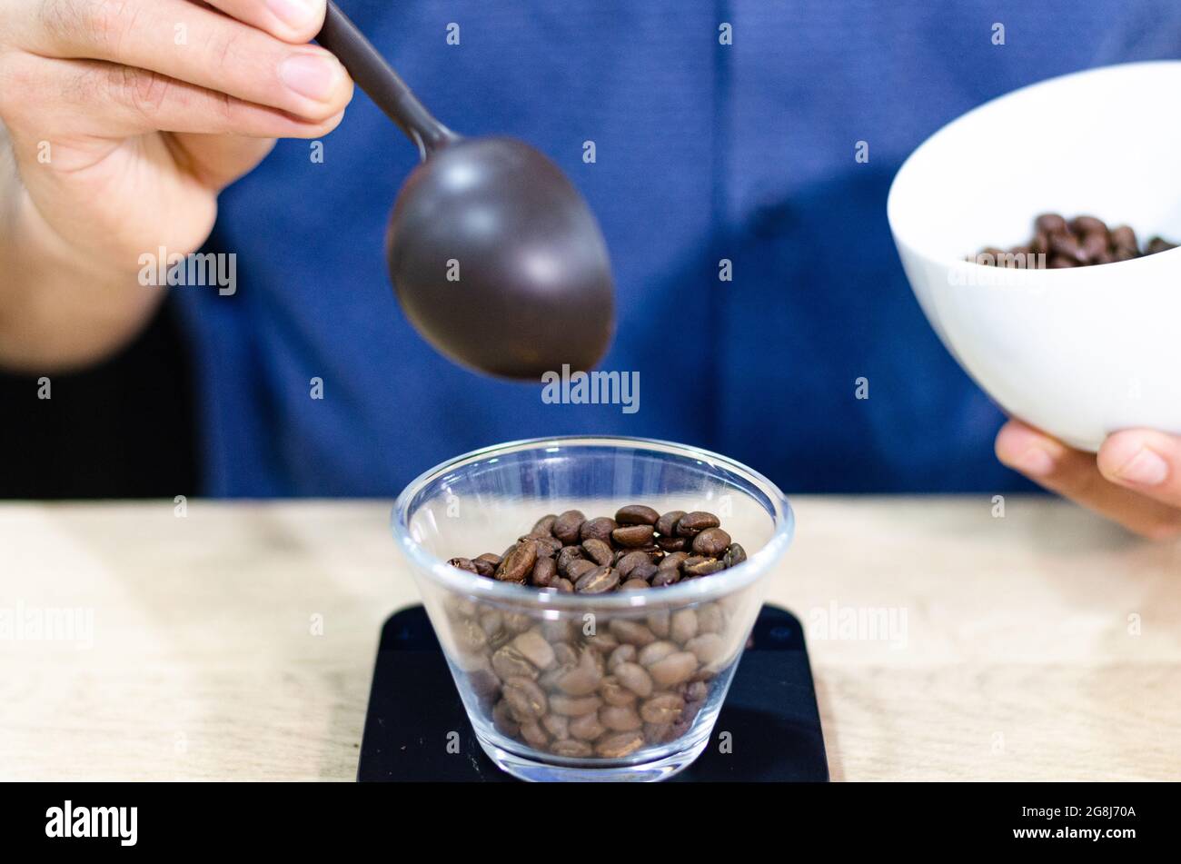 Weighing coffee grains on digital scale. Hands of male barista pouring roasted coffee grains on a scale before brewing coffee. Stock Photo