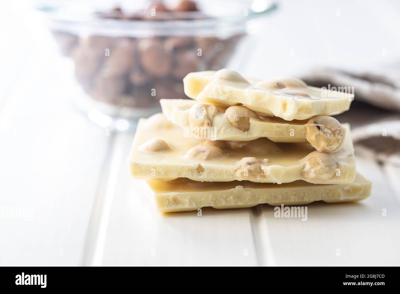 White chocolate bar with hazelnuts on white table. Stock Photo
