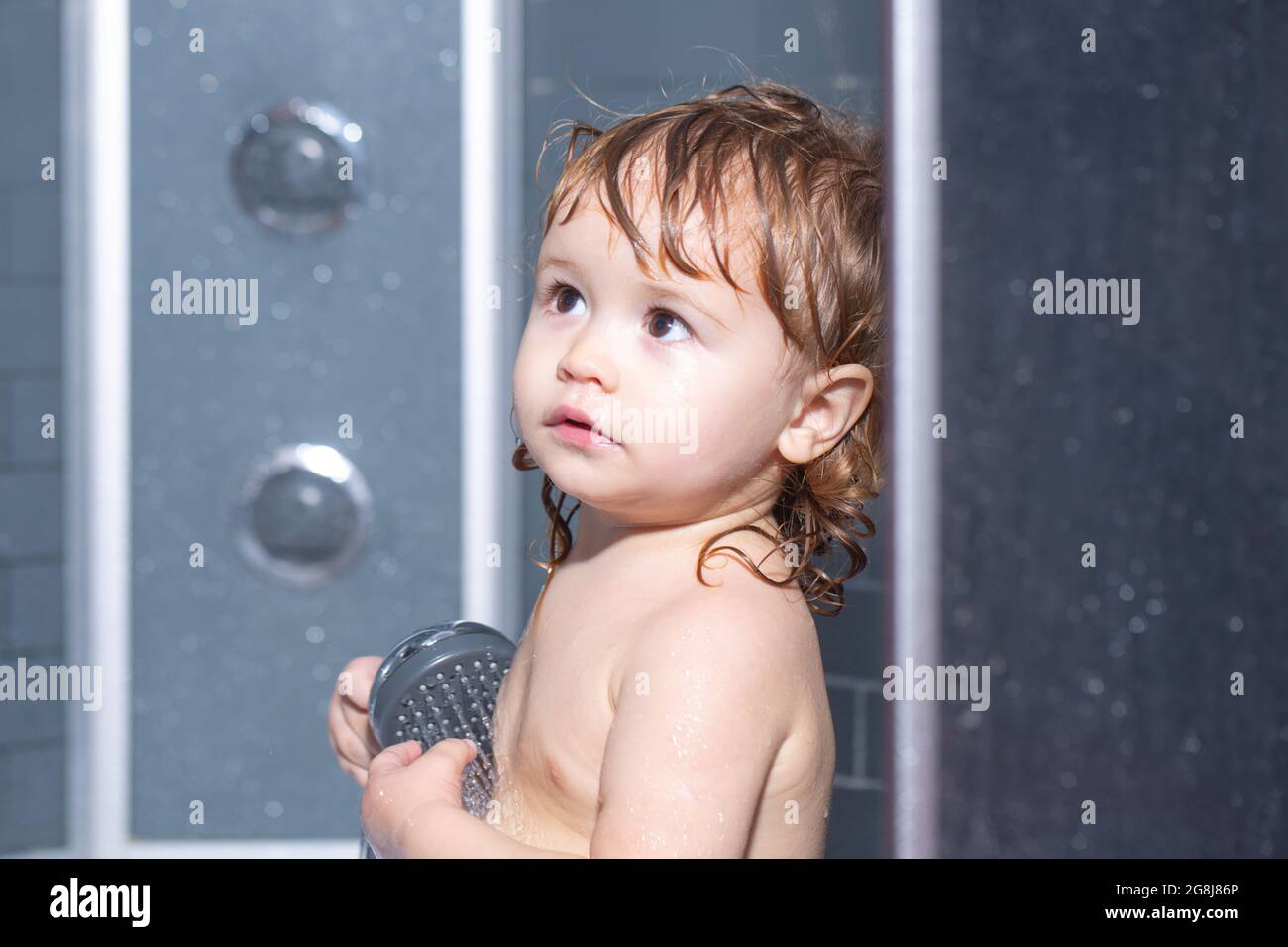 Child bathing in bathroom. Funny baby kid bathed in foam and washing in