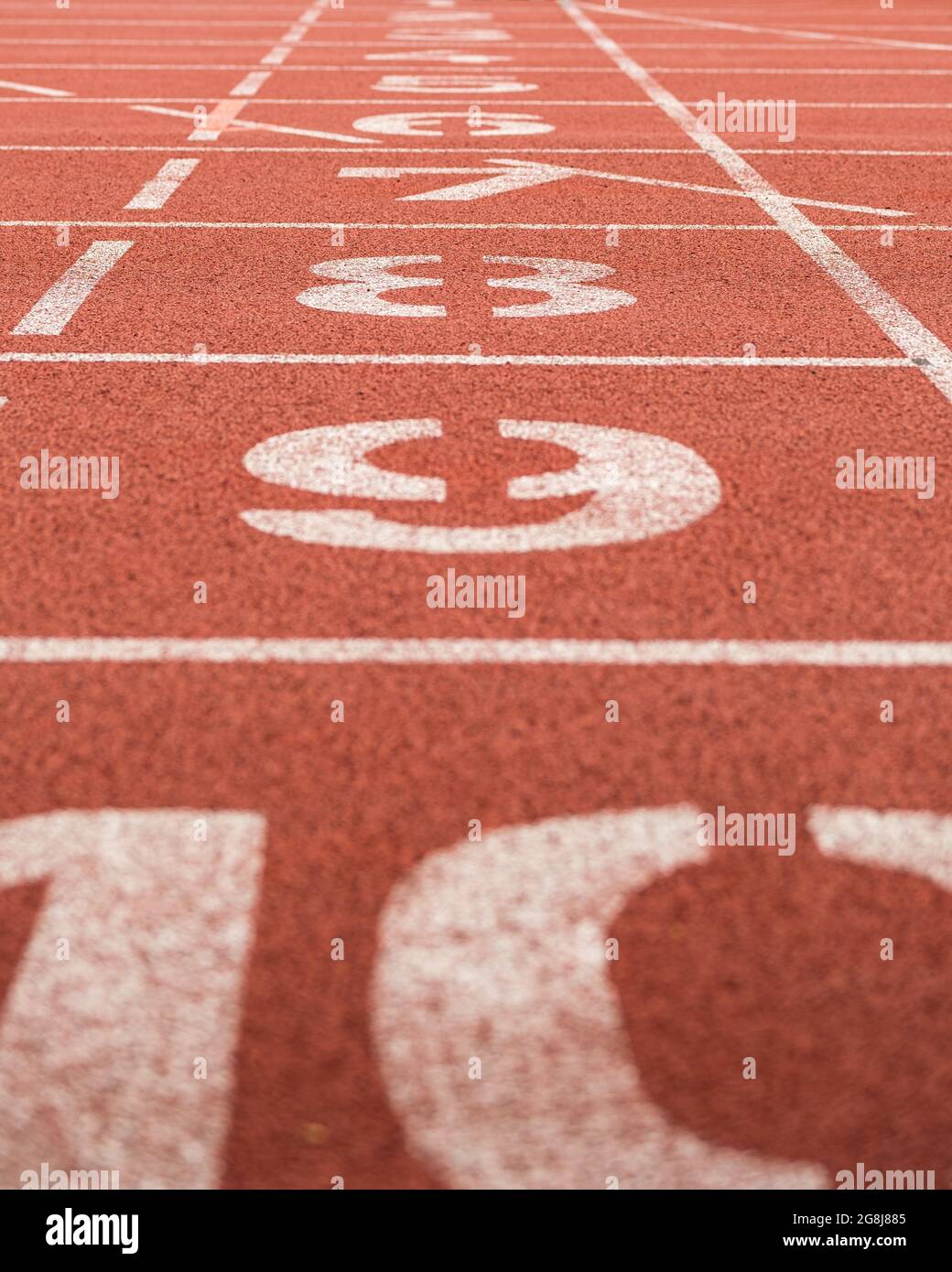 Sideview on lane numbers at the finish of red race track (running track or athletics track), shallow depth of field Stock Photo