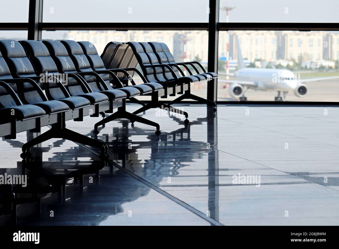 Empty waiting chairs in the airport building against the plane on runway. Travel during quarantine at coronavirus pandemic Stock Photo