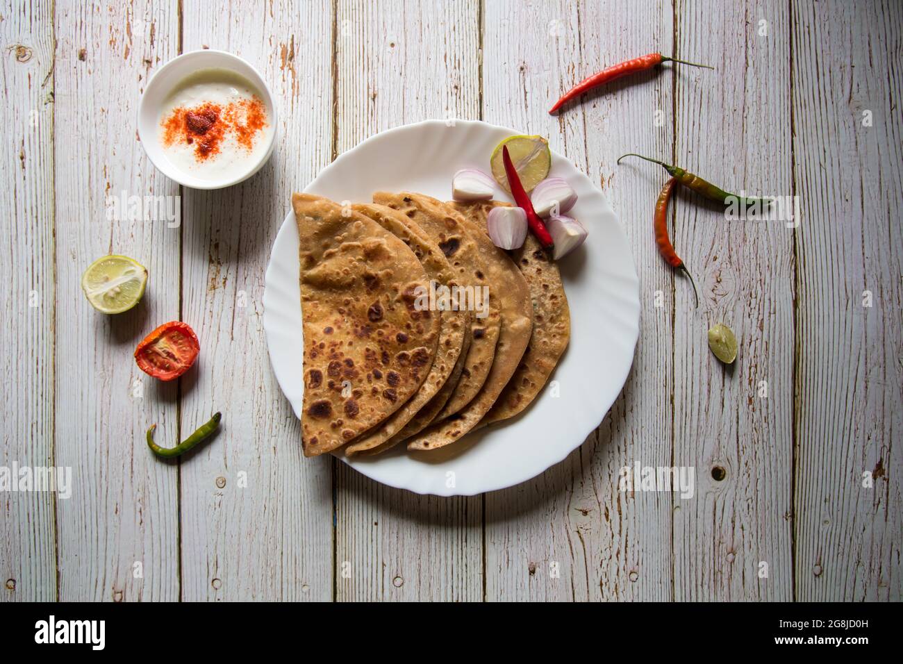 Stuffed potato or aloo paratha served with condiments and curd. An