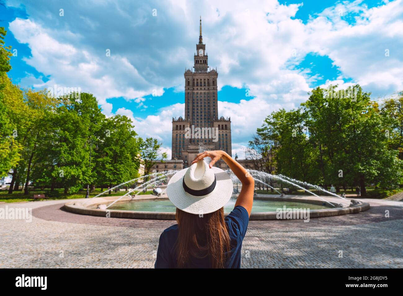 Young tourist woman in white sun hat walking in the park near Palace of Culture and Science in Warsaw city, Poland. Summer vacation in Warsaw Stock Photo