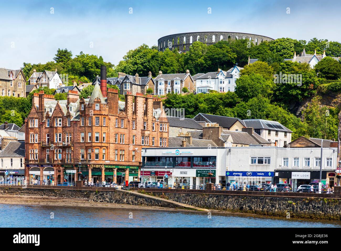 Oban promenade and esplanade with a view of Argyll Mansions and McCaigs Folly on Battery Hill overlooking the town, Oban, Argyll, Scotland, UK Stock Photo