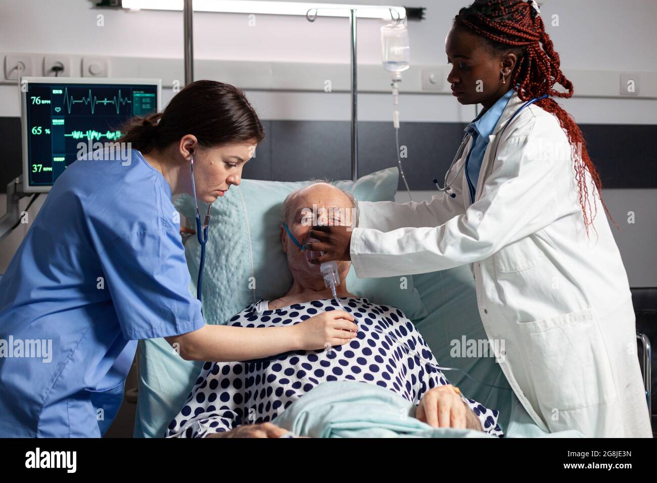 African doctor and medical assistant helping senior man breath using