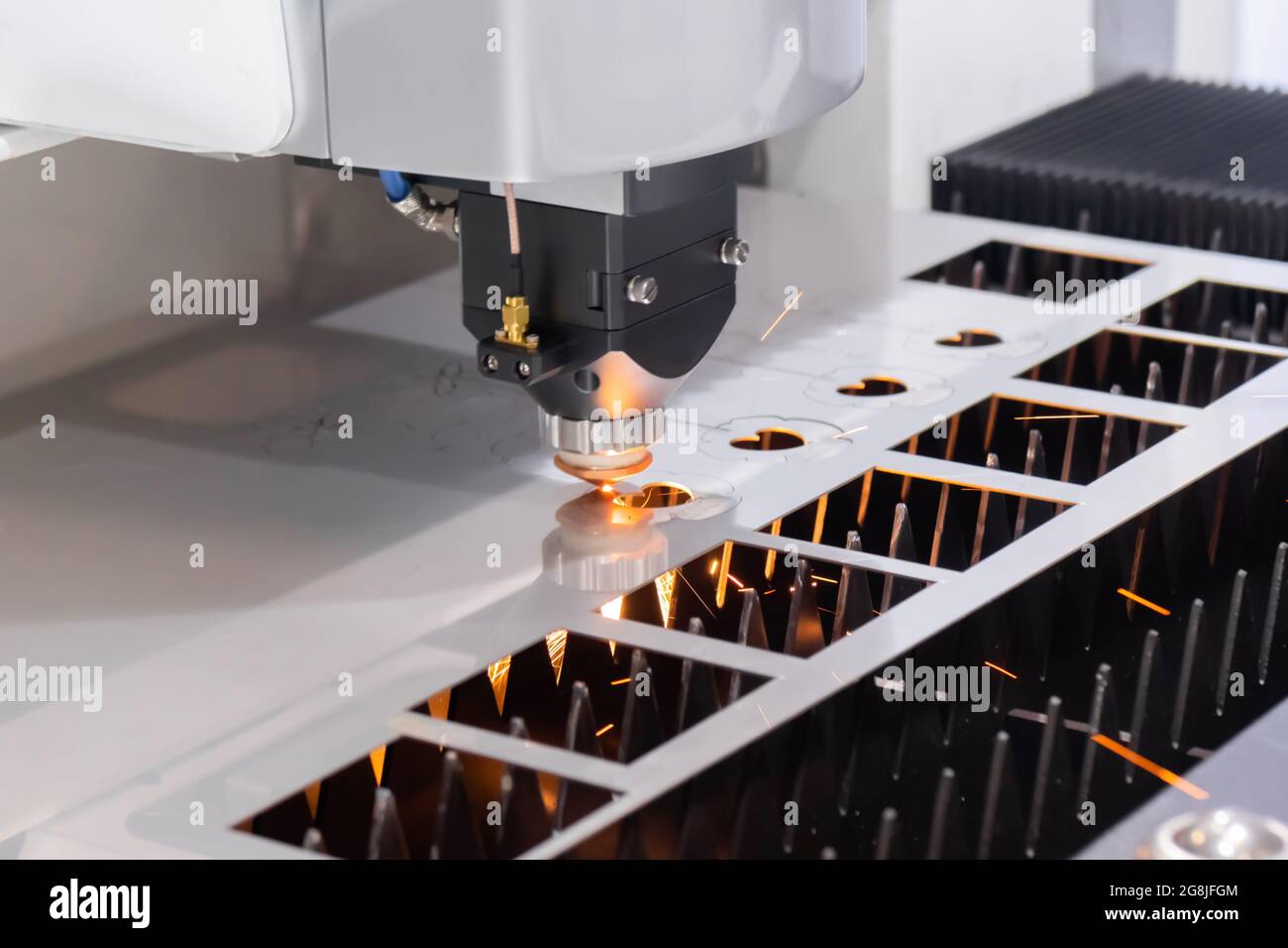 Laser cutting machine working with sheet metal with sparks at factory