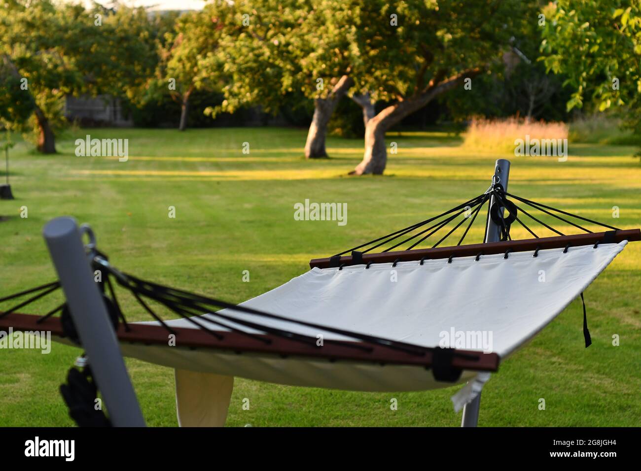 A view of a relaxing empty hammock on a summers afternoon in the UK looking down a green garden Stock Photo