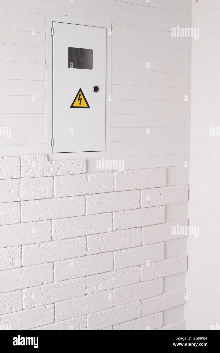 Box for electrical machines and a meter. The brickwork on the wall is white. Electricity Stock Photo