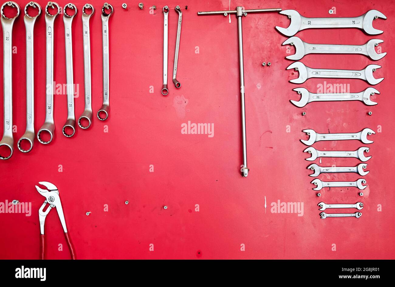 Various work tools hanging on a red stand at the car service workshop. Stock Photo