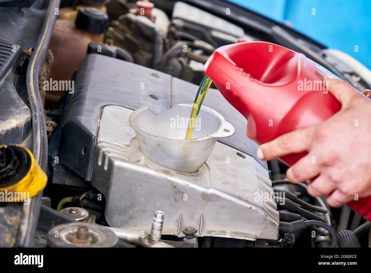 Hands of a mechanic repairman adding or pouring oil to the car engine