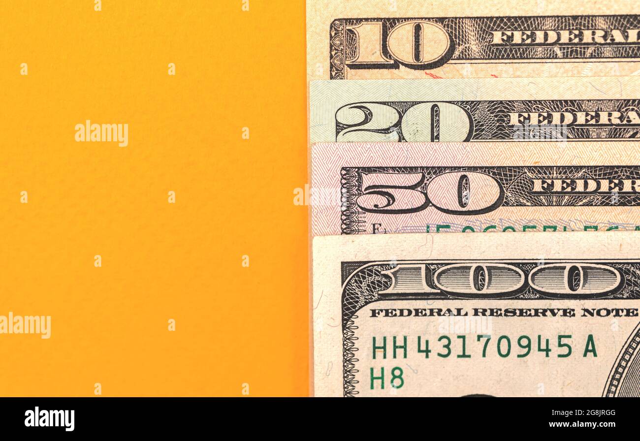 Dollar banknotes 10, 20, 50 and 100 denomination closeup on a desktop yellow background Stock Photo