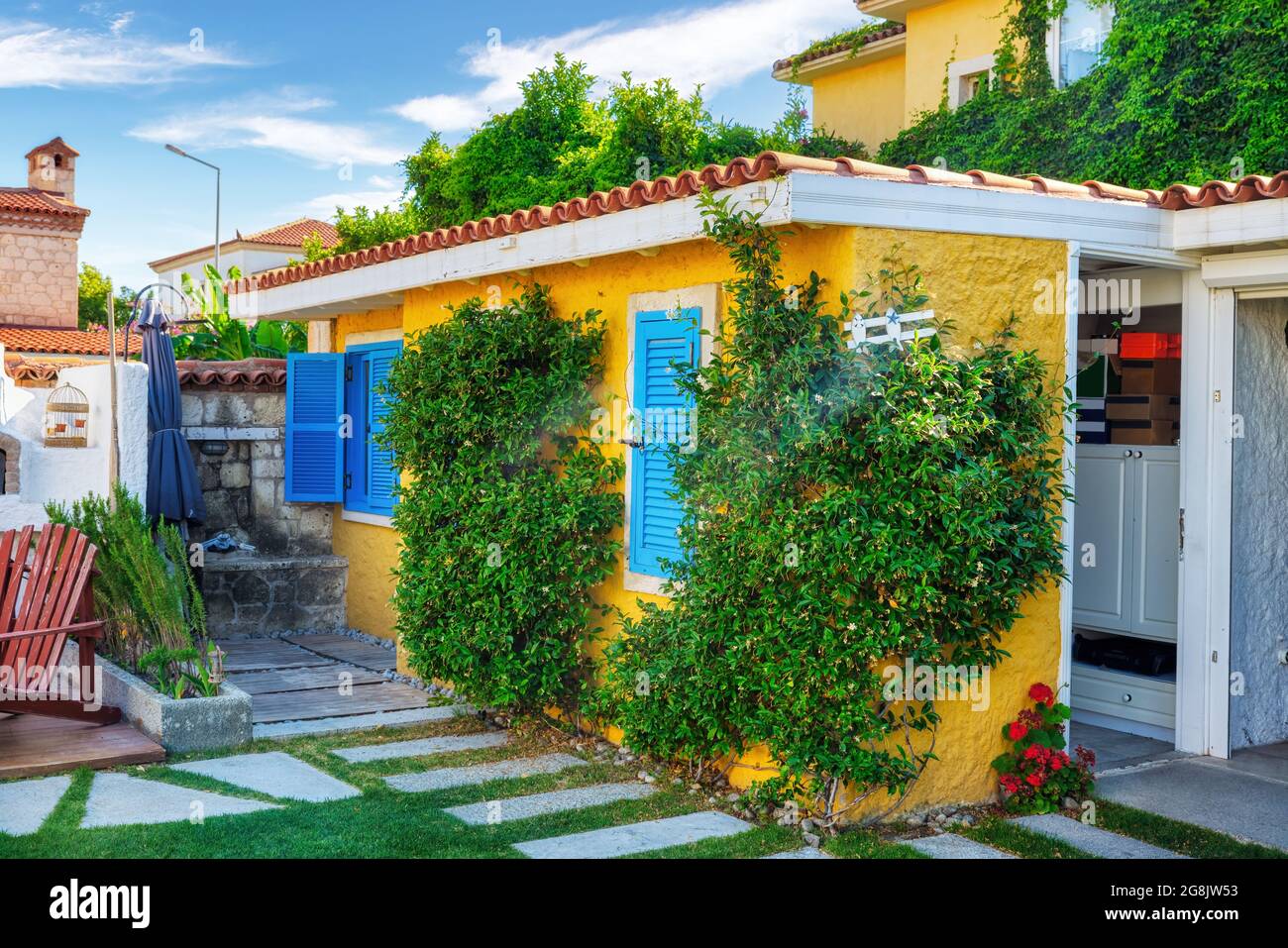 Traditional Aegean village house with yellow walls, blue shutters and