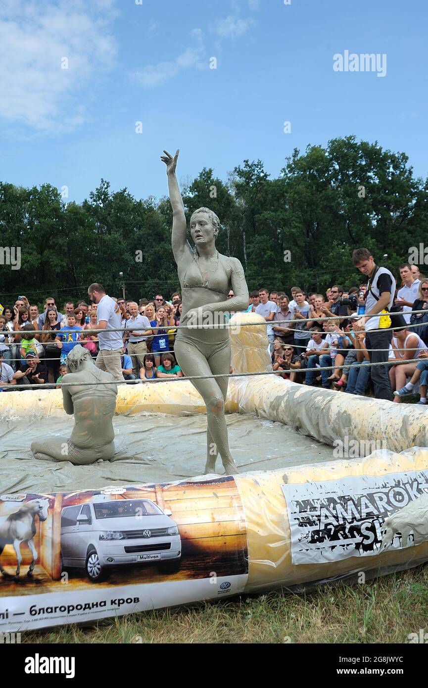 Mud girl claims victory in the ring, crowd of people watching. Mud wrestling show. June 23, 2017. Kiev, Ukraine Stock Photo