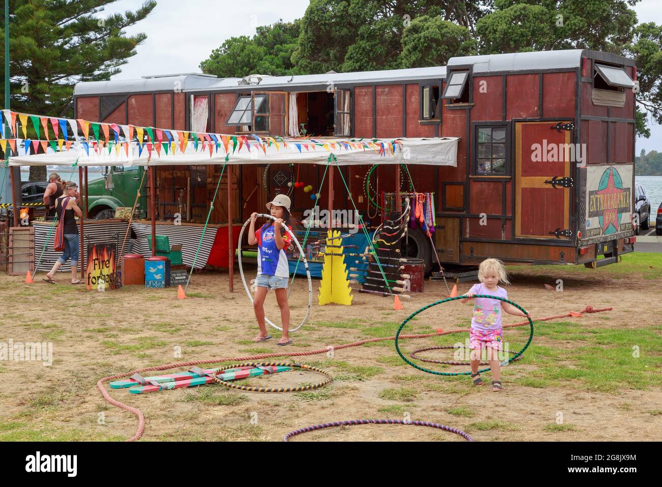 Young girls playing with hula hoops beside the caravans of a traveling fair Stock Photo