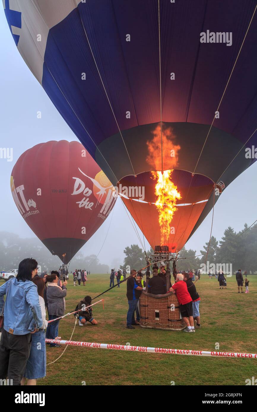 Hot air balloons, one being inflated by a burst of flame from a burner