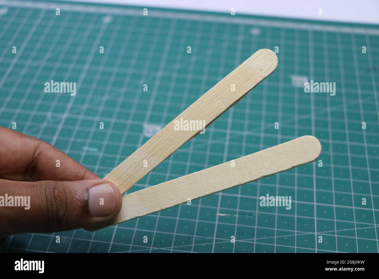 Hand holding pair of ice cream sticks for making crafts and other decoration projects Stock Photo